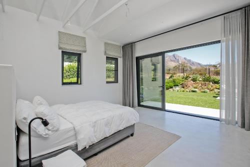 a white bedroom with a bed and a large window at Table Mountain and Constantiaberg view in Sweet Valley