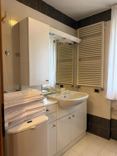 a white bathroom with a sink and a mirror at Campiglio Bilocale Dolomiti in Madonna di Campiglio