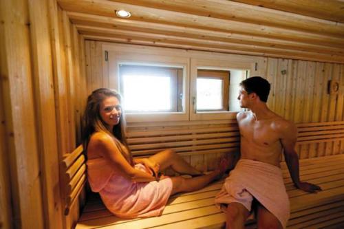 a man and a woman sitting in a sauna at Victoria Camping Bella Austria in Peterdorf
