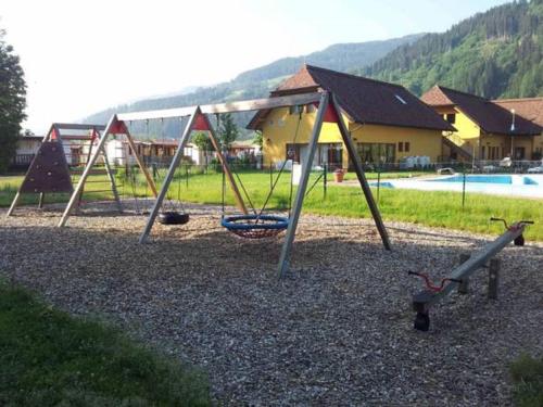 a playground with a swing set and a pool at Victoria Camping Bella Austria in Peterdorf