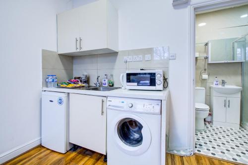 a kitchen with a washing machine and a microwave at London Brompton Residence Hotel in London