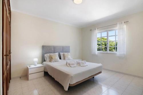 a white bedroom with a bed and a window at Casa da Audiência Lote 32 in Monte Gordo