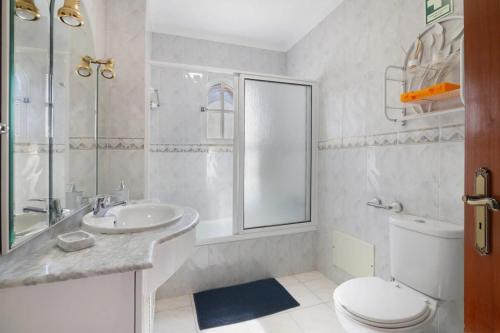 a white bathroom with a toilet and a sink at Casa da Audiência Lote 32 in Monte Gordo