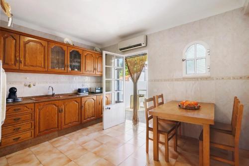 a kitchen with wooden cabinets and a wooden table at Casa da Audiência Lote 32 in Monte Gordo