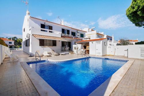a villa with a swimming pool in front of a house at Casa da Audiência Lote 32 in Monte Gordo