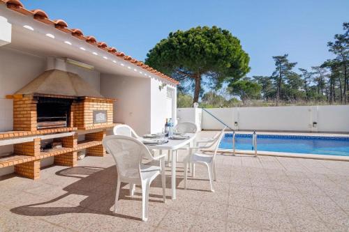 a patio with a table and chairs next to a pool at Casa da Audiência Lote 32 in Monte Gordo