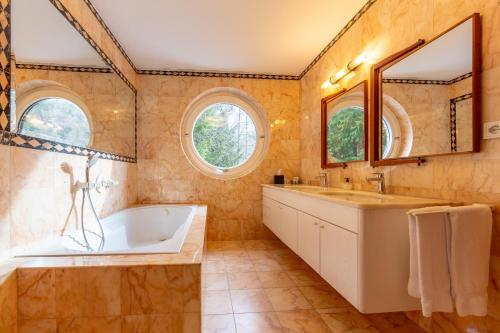 a bathroom with a tub and a sink and two windows at Parkhotel Sole Paradiso in San Candido