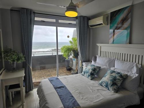 a bedroom with a bed with a view of the ocean at Flat 108 Cozumel, Umdloti Beach Front in Umdloti