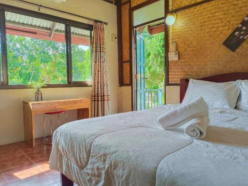 a bedroom with a bed and a desk and a window at Pai Tewdoi ปาย ทิวดอย รีสอร์ท in Pai