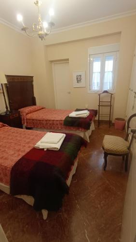 a room with three beds and a chair and a chandelier at Precioso Piso junto a Plaza de España in Seville