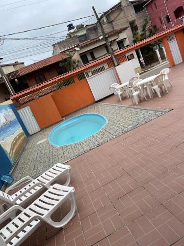 a patio with lounge chairs and a swimming pool at Pousada Mirante do Sol in Piúma