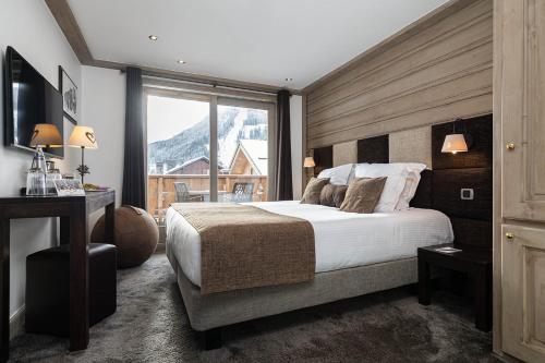 a bedroom with a large bed and a large window at Hotel La Chaudanne in Méribel