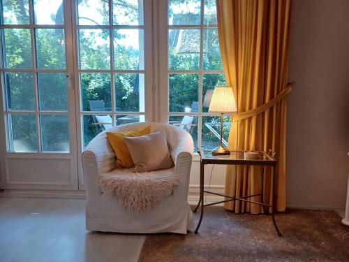 a living room with a chair and a table and windows at Achtern - Diek - am Strand in Zingst
