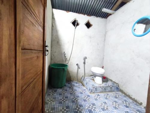 a bathroom with a toilet next to a door at Nadi awin kamam in Fambemuk