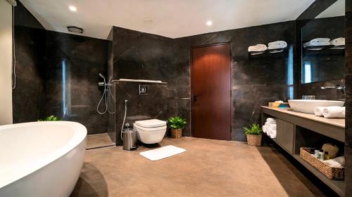 a bathroom with a tub and a toilet and a sink at Trinity Hotel Banquet & Spa in Siliguri