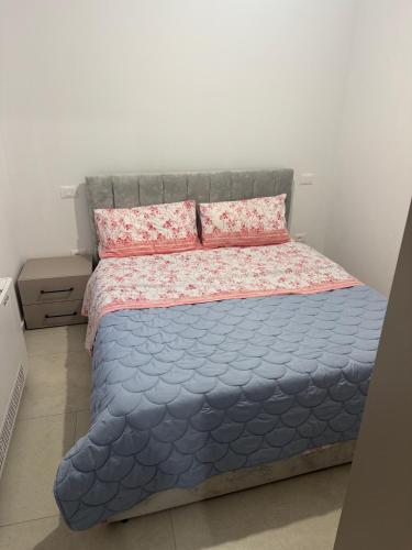 a bedroom with a bed with a blue comforter and pink pillows at KEAN Apartments in Vlorë