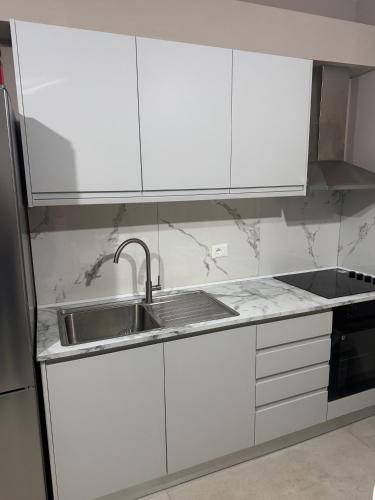 a kitchen with white cabinets and a stainless steel sink at KEAN Apartments in Vlorë