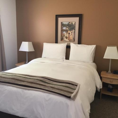 a bedroom with a large white bed with two lamps at Driftwood by the Sea Inn in Campbell River