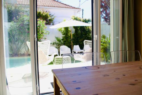 a dining room table with a view of a patio at White and Light House in Costa da Caparica