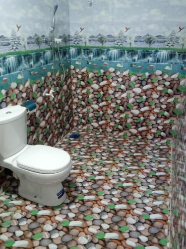 a bathroom with a toilet and a wall of rocks at U new guest house in Nilaveli