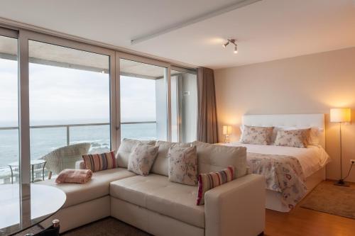 a living room with a white couch and a bed at Bartolomeu Beach Apartments in Porto