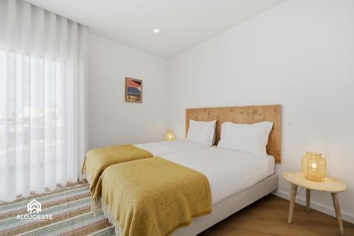 a bedroom with a white bed with a yellow blanket at Atlantic Apartments in Santa Cruz
