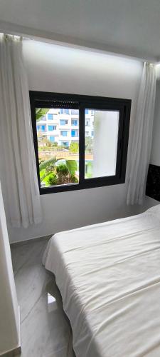 a bedroom with a white bed and a window at Élégant appartement de 3 chambres vue piscine n4 in M'diq