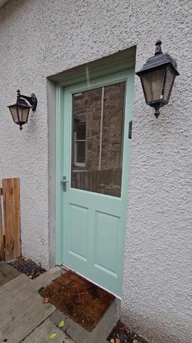 a blue door on a white building with two lights at The Wee Corsee Cosy Coastal Cottage in the Heart of Nairn in Nairn