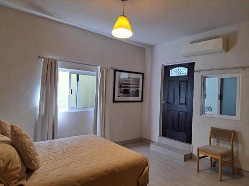 a bedroom with a bed and a door and a chair at Alojamiento Privado San Jose Viejo BCS in San José del Cabo