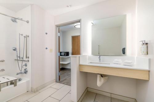 a bathroom with a sink and a tub and a mirror at Holiday Inn Express & Suites - Medford by IHG in Medford