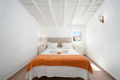 a white bedroom with a large bed with orange blanket at Casa Morais in Odeceixe