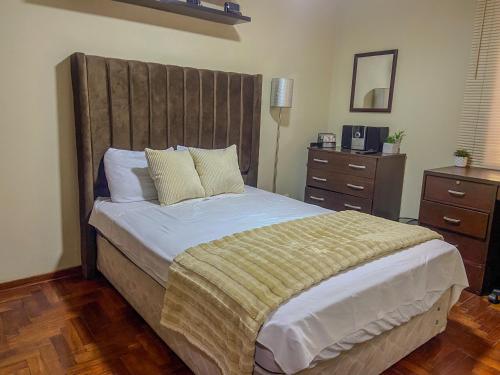 a bedroom with a large bed with a wooden headboard at High Garden Apartment in Trujillo