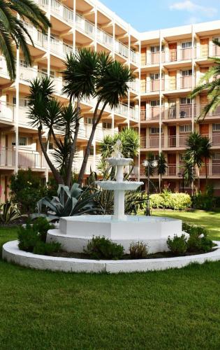 a fountain in front of a large apartment building at Apartamento Paradis Playa in La Pineda