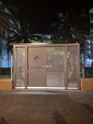 a gate at night with a palm tree behind it at Apartamento Paradis Playa in La Pineda