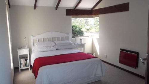 a bedroom with a white bed with a red blanket at Selah Sands in Port Alfred