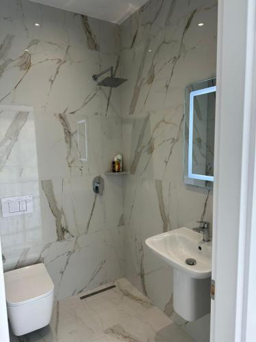 a white bathroom with a sink and a toilet at guest house Qyteza in Shkodër