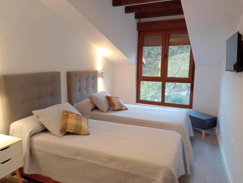 a bedroom with two beds and a window at Apartamentos Antuña in Cangas de Onís