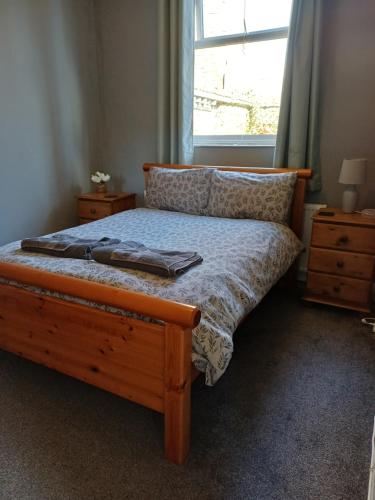 a bedroom with a bed with a wooden frame and a window at Home from Home in Faversham