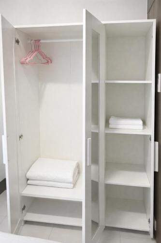 a white closet with white shelves and white towels at Casa MJ Suites at SMDC Fame Residences, Mandaluyong in Manila