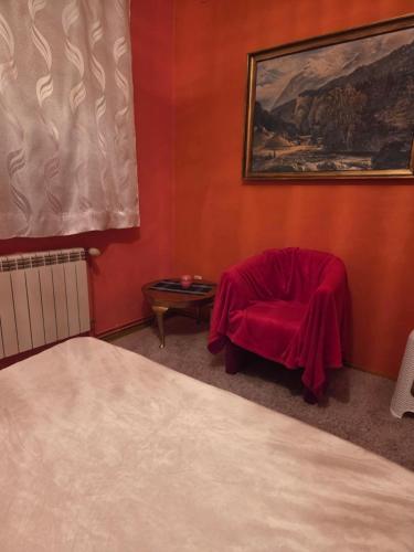 a red room with a chair with a blanket on it at Apartament Wiejska 5a in Ciechocinek