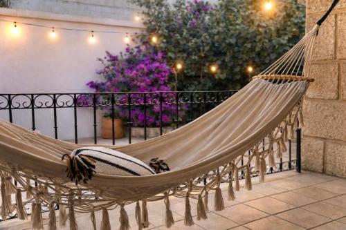 a hammock on a balcony with purple flowers at Casa Ritual tu refugio con jardín & 4 recámaras in Oaxaca City