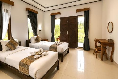 a hotel room with two beds and a desk at Indra Yoga Retreat in Selemadeg