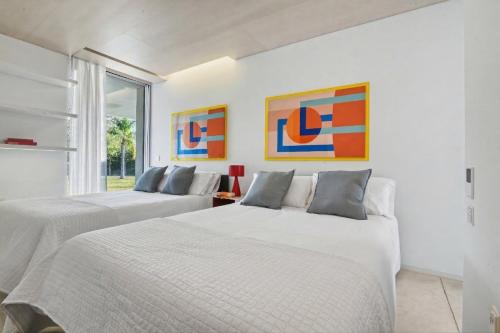 two beds in a white room with paintings on the wall at Casa Torus Luxury Design Villa with Private SPA & Cinema in Jávea