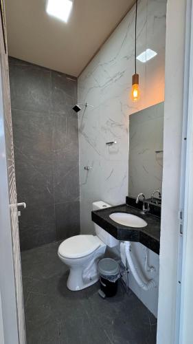 a bathroom with a white toilet and a sink at Chácara Santa Fé in Iguatu