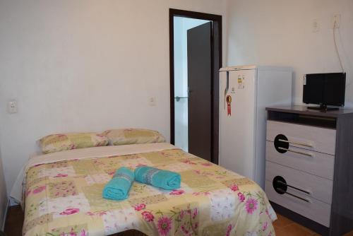 1 dormitorio con 1 cama con 2 zapatillas azules en Residencial Dom Celeste, en Canela