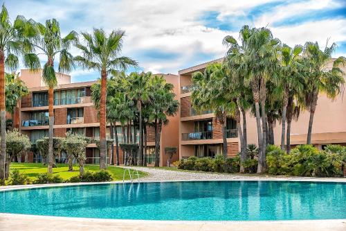 an apartment building with a swimming pool and palm trees at Herdade dos Salgados Beach apartment in Albufeira
