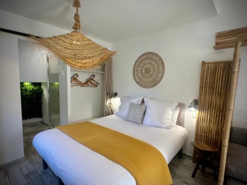 a bedroom with a white bed with a yellow blanket at Hôtel Le Clos du Dramont in Saint-Raphaël