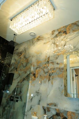 a chandelier hanging from a ceiling with a marble wall at Heathrow Royal Apartment in Ashford