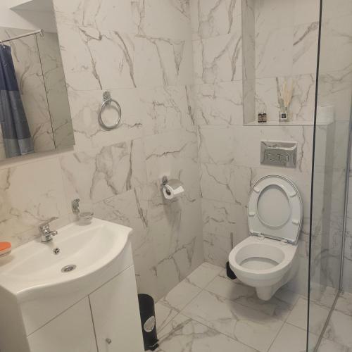 a white bathroom with a toilet and a sink at New studio in Râmnicu Vâlcea