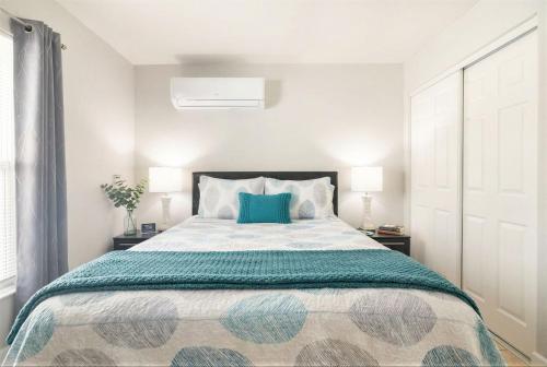a white bedroom with a large bed with blue pillows at Modern Studio Near Busch Gardens Tampa in Tampa